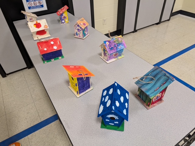 Nueve coloridas casitas para pájaros hechas a mano expuestas juntas sobre una mesa durante una actividad con motivo del Día de la Tierra en el Northwest Center for Autism.