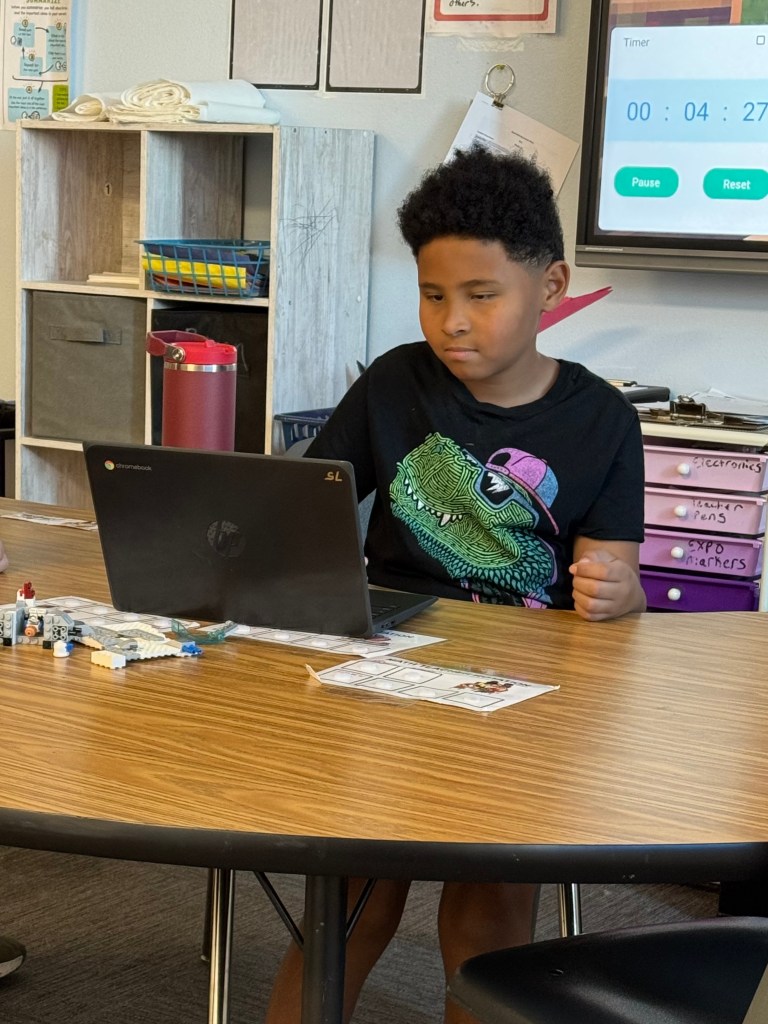 Student working independently on a laptop at his classroom desk.