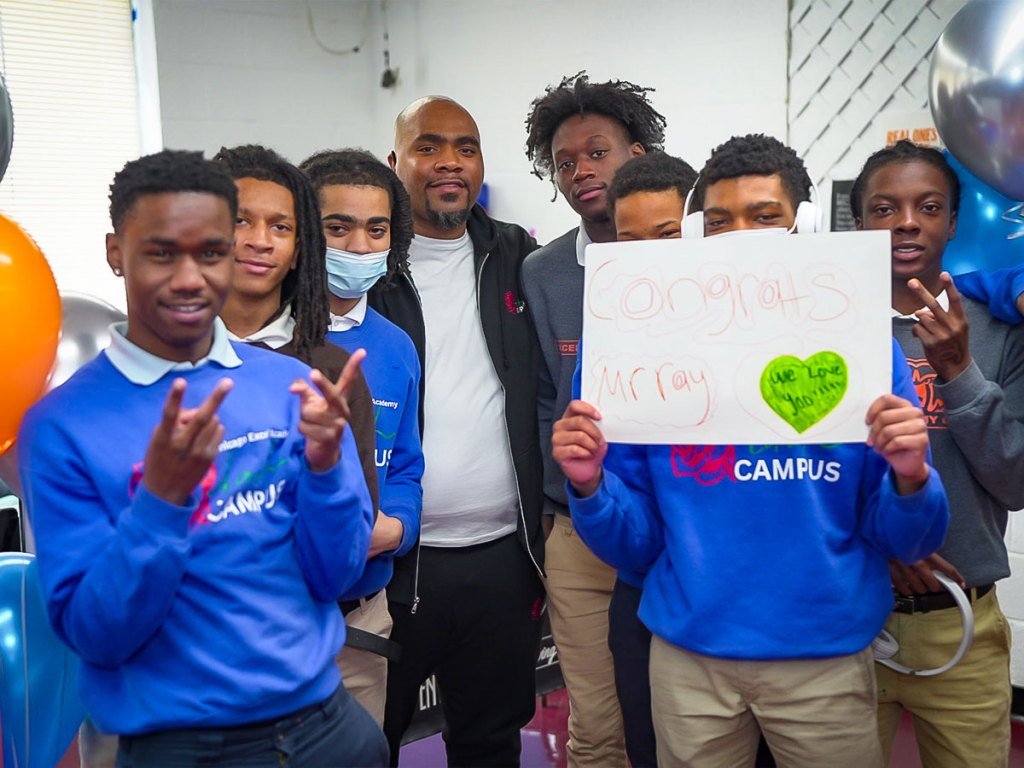 Raynard Gillispie posing with students holding a congratulatory sign after being named SESI’s 2026 Staff of the Year.