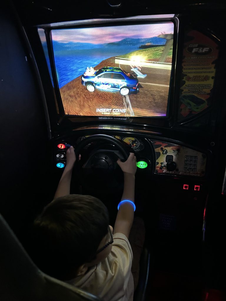 Student playing driving arcade game during Fun Friday event at 3D Mini Golf in Gilbert, Arizona.