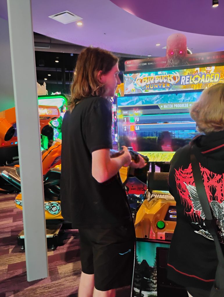 obi plays an arcade shooting game at a video game arcade.