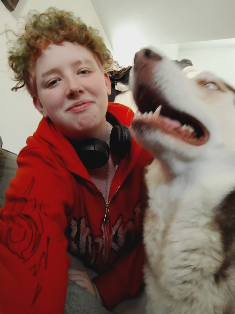 A smiling individual poses beside a dog outdoors.