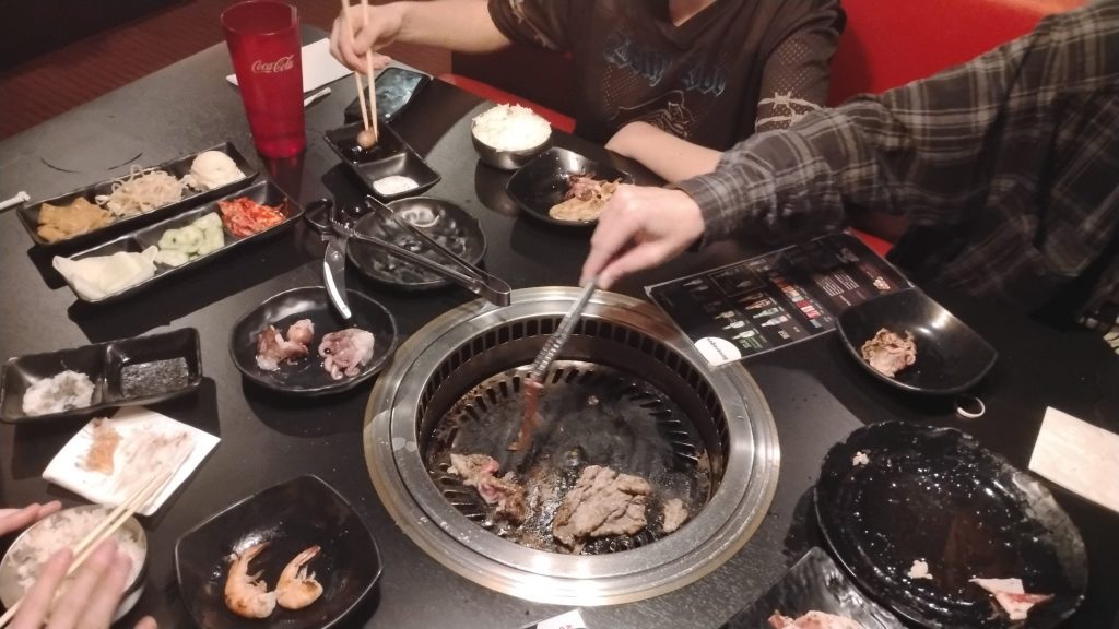 Assorted meats and side dishes displayed on a restaurant table during a shared dining experience.