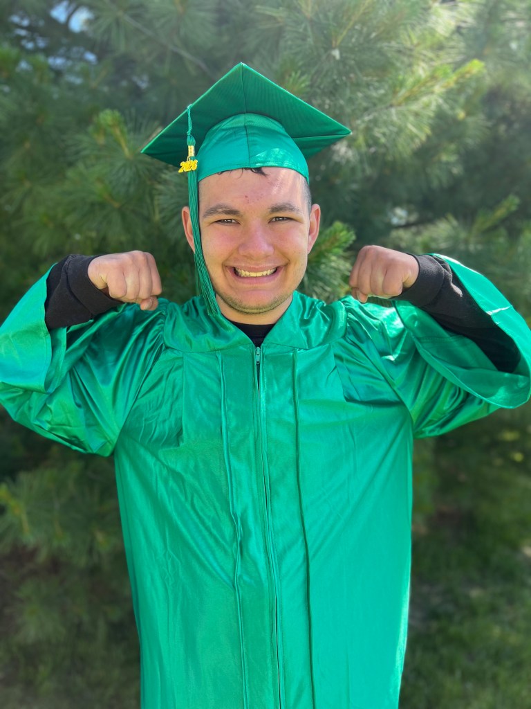 Student celebrating graduation in a green cap and gown at High Road School of Wright City