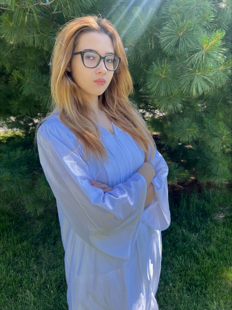 Graduate in a white gown posing outdoors during the Wright City graduation ceremony