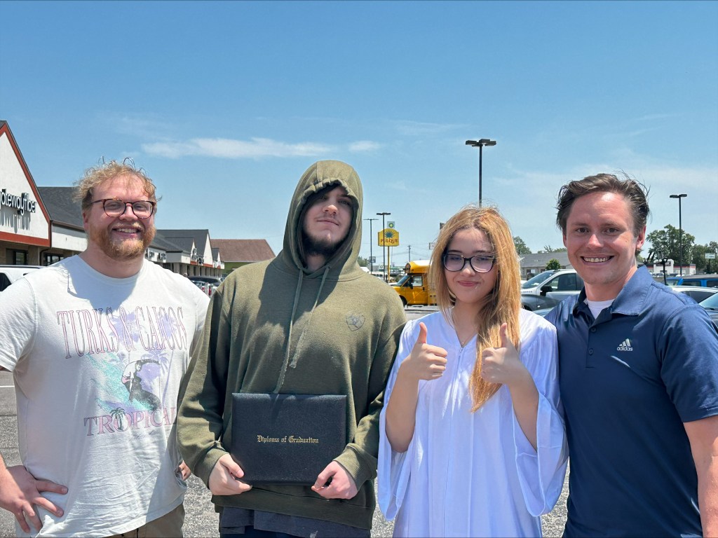 Graduates standing together during the outdoor High Road School graduation ceremony