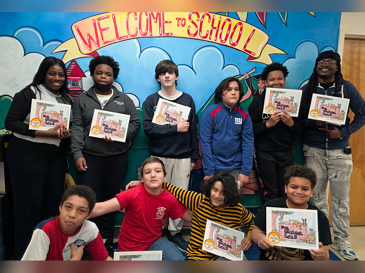 Students proudly holding copies of their My Unique Self books in front of a welcome wall at High Road School of Wallingford.