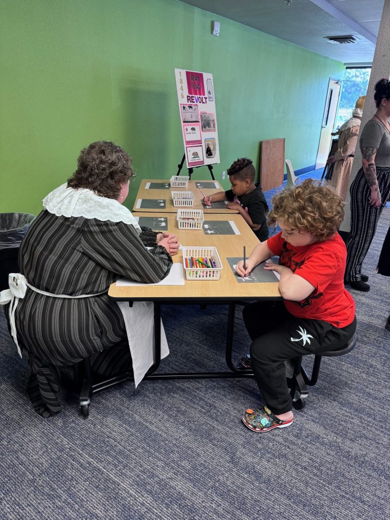 Students coloring at desks during a California history exhibition at Sierra School of Solano County