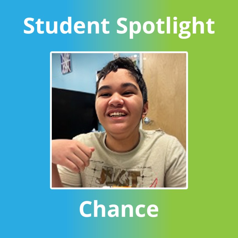 Student proudly holding a basic circuit project with wires, connectors, and a battery in the classroom