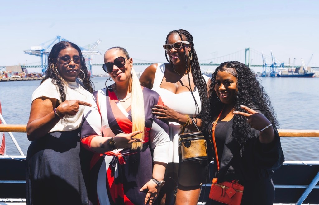 Students and staff posing for a photo with the Philadelphia waterfront in the background.
