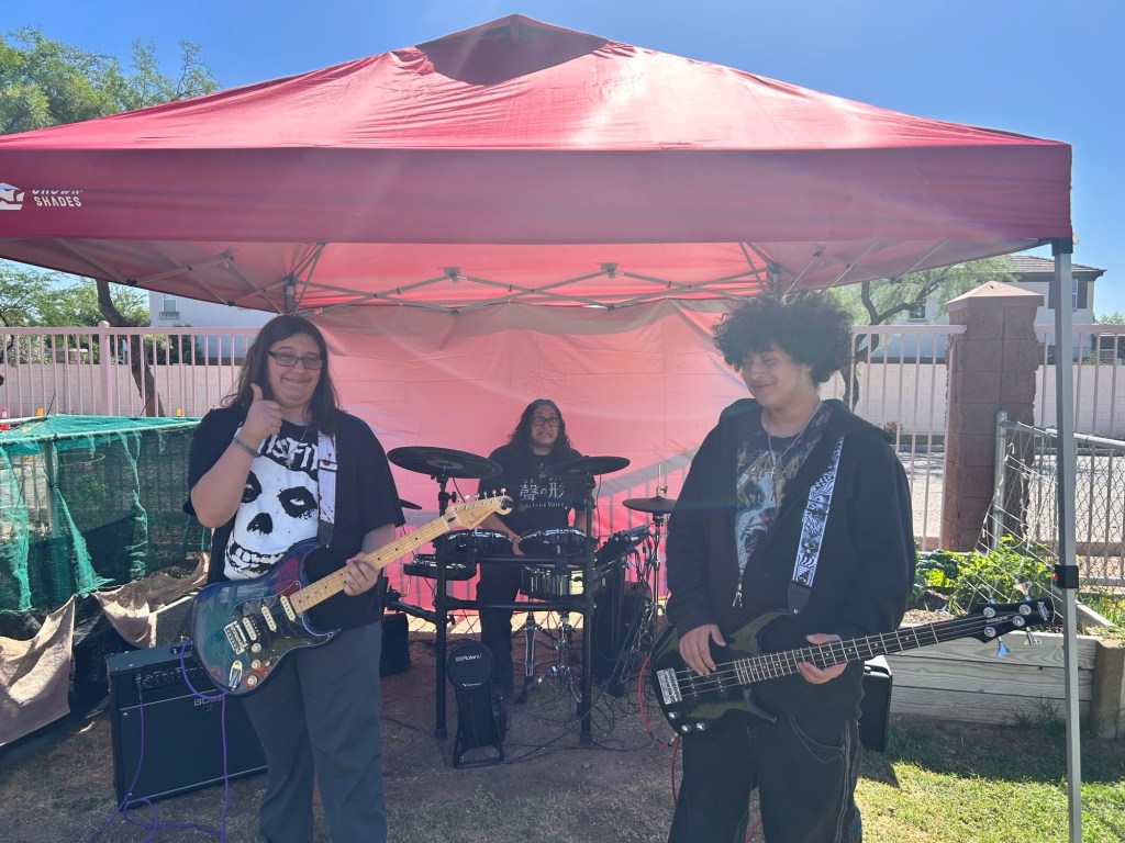 La banda de estudiantes, sonriente y tocando durante el evento al aire libre «Summer Splash Bash» de Sierra Gilbert.