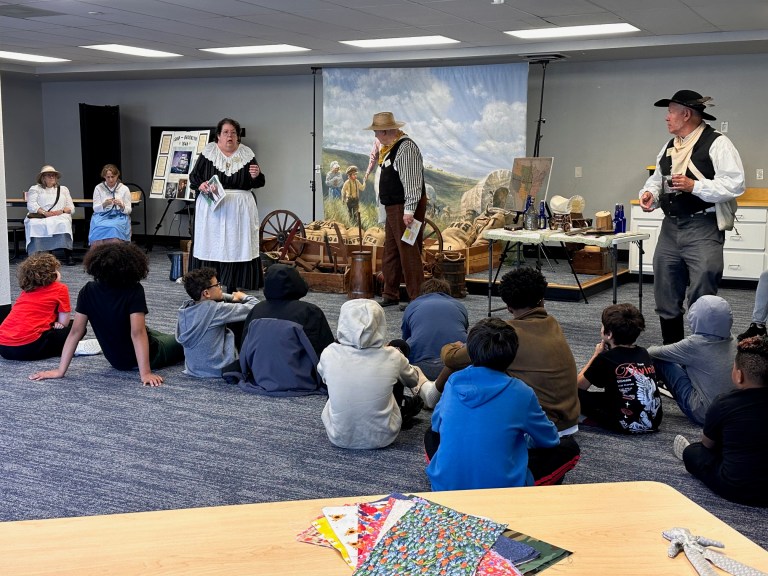 Students listening to exhibitors present historical artifacts during a living history lesson