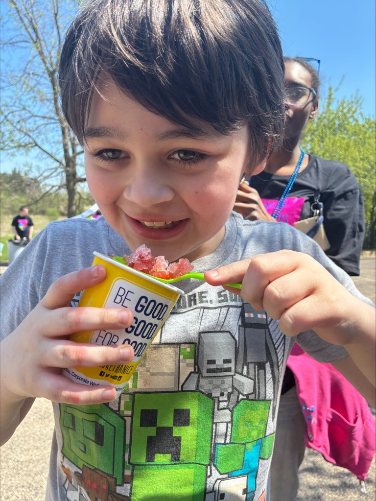 Student smiling while enjoying Kona Ice during the school’s Autism Walk celebration.