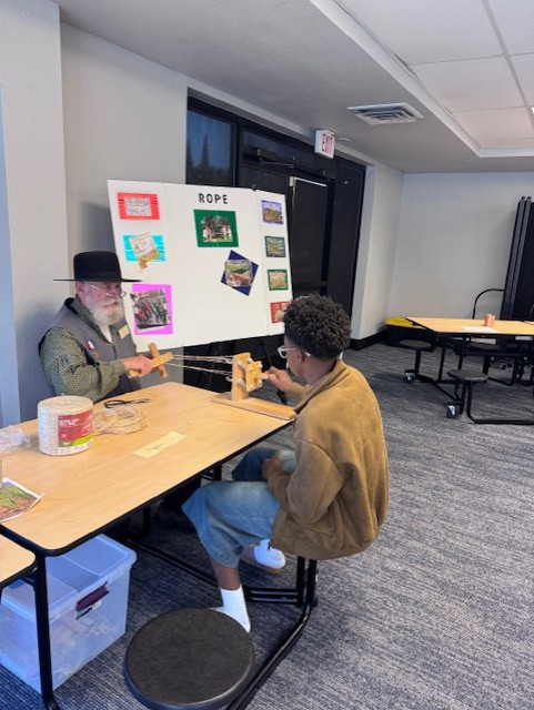 Student participating in a hands-on history activity with an exhibitor