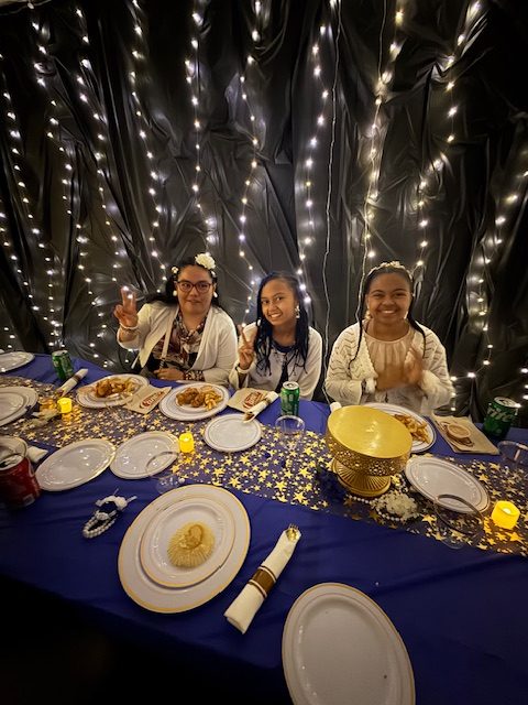 Students seated at a decorated table with food during school prom event
