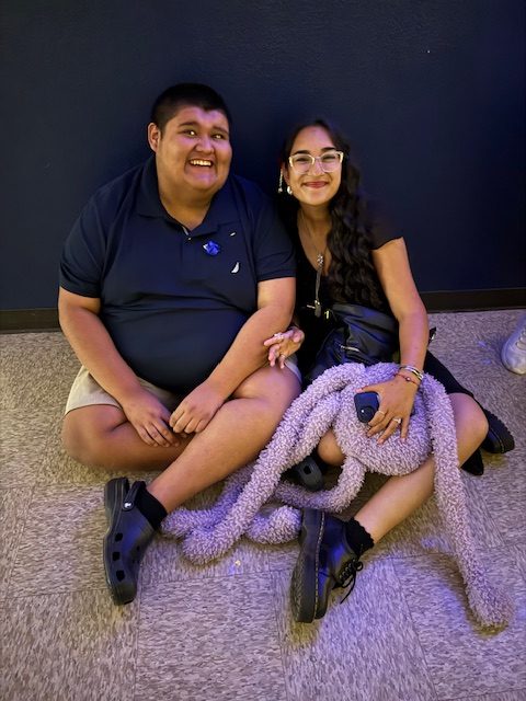 Two students sitting together on the floor smiling during prom celebration