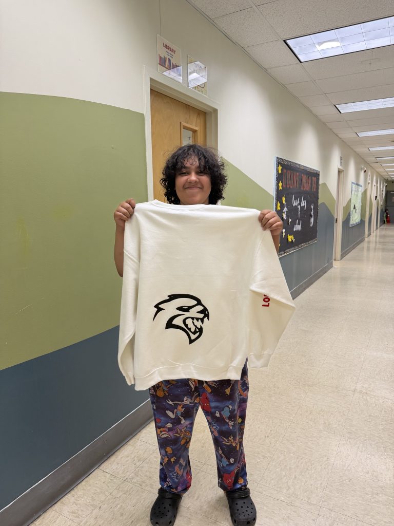 Un alumno luce con orgullo una sudadera hecha a medida con un diseño gráfico personalizado creado durante el proyecto de clase.