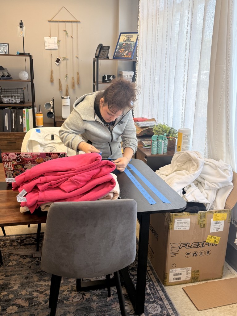 El alumno prepara los materiales y los elementos de diseño de la sudadera mientras trabaja en la fase práctica de producción del proyecto.