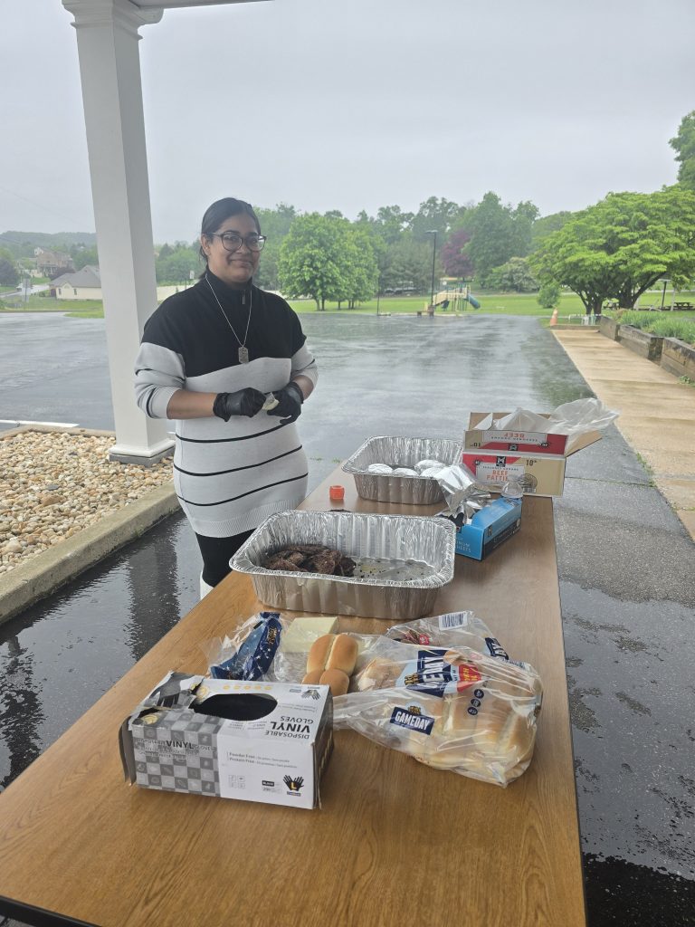 Un estudiante voluntario prepara hamburguesas y todo lo necesario para la barbacoa durante la fiesta de fin de curso de la High Road School de York.