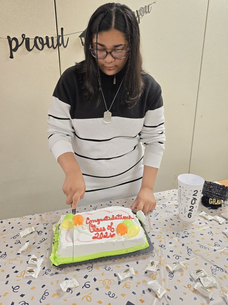Un graduado corta la tarta durante la fiesta de fin de curso para los alumnos de último curso.