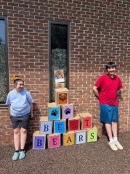 Students posing beside a colorful BEST Bears field day display.