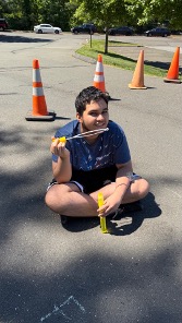 Student sitting near the obstacle course during an outdoor field day activity.