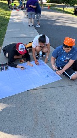 Students working together to decorate a team flag with markers.