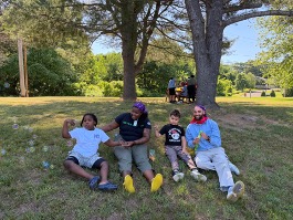 Students and staff relaxing together beneath a tree during field day.
