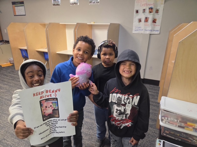 Students display a classroom project and learning goal before participating in a STEAM field trip to Chuck E. Cheese.
