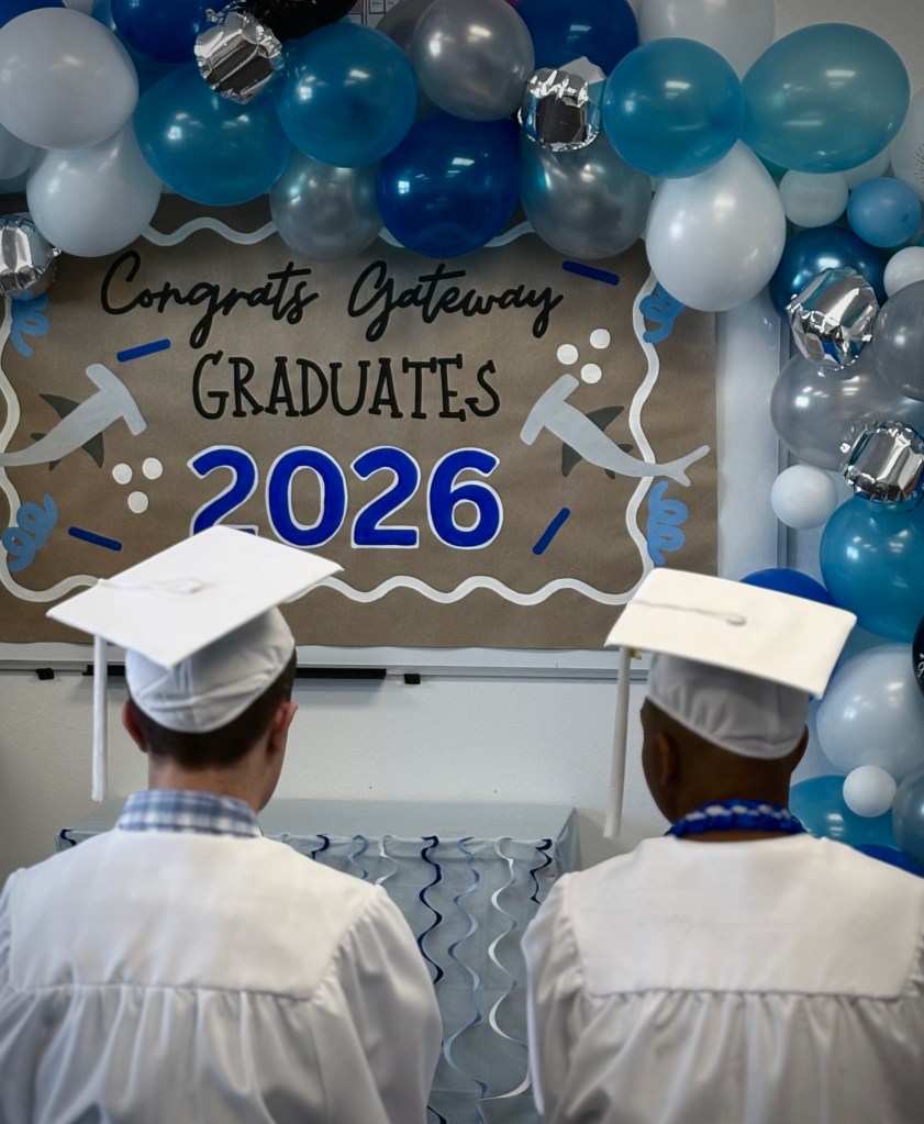 Sierra School of Gateway graduates sit before a decorated Class of 2026 backdrop during the graduation ceremony.