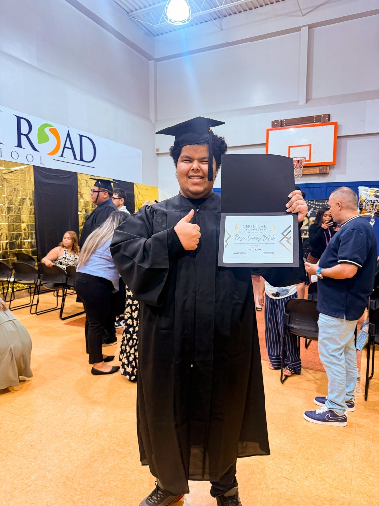 Un graduado de la High Road School de Hartford, sonriendo y sosteniendo su título tras la ceremonia de la promoción de 2026.