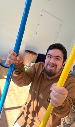 Matthew smiling while holding two colorful activity poles.