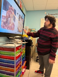 Matthew pointing toward a classroom screen during a learning activity.