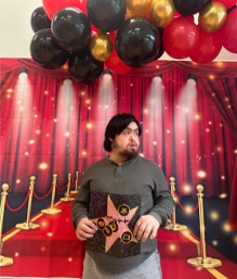 Matthew holding a BEST award at a red-carpet-themed school celebration.