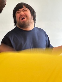 Matthew smiling and laughing during an activity with staff.