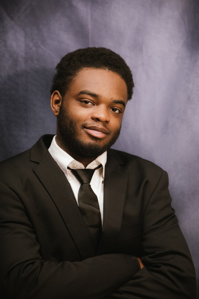 Nasir Knox posa para una foto oficial de graduación vestido con traje negro y corbata.