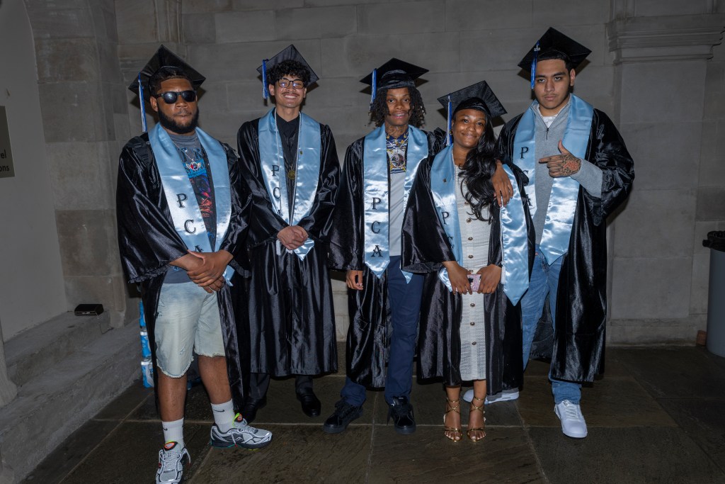 Philadelphia graduates wearing caps, gowns and light blue stoles pose together after the ceremony.