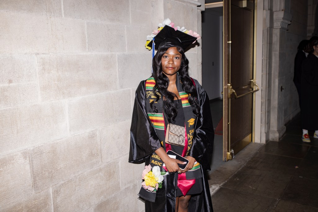Class of 2026 graduate wearing a decorated stole and holding flowers at Temple Performing Arts Center.