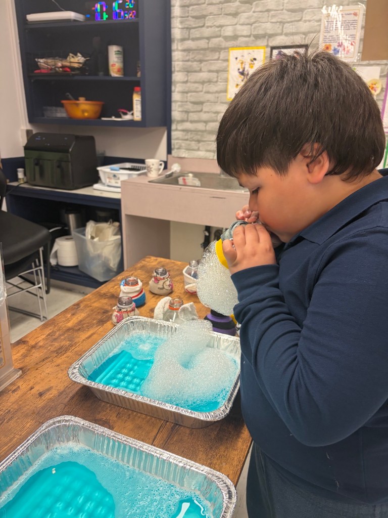 Un alumno participa en una actividad científica con pompas de jabón durante la Feria S.T.E.A.M. de Primaria de la High Road School de Hartford.