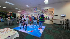 Los alumnos disfrutan de una actividad de baile en grupo con Chuck E. Cheese durante una jornada de aprendizaje y diversión inspirada en STEAM.
