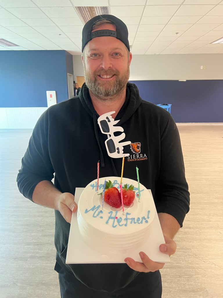 Dustin Hefner holds a welcome cake after being named school director at Sierra School of San Joaquin.