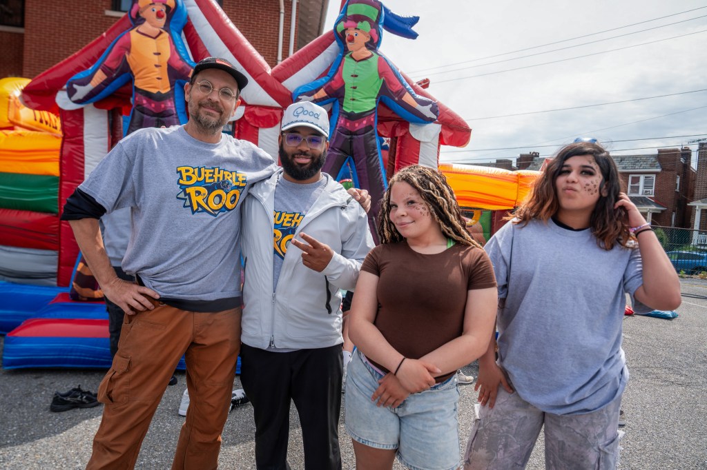 Los alumnos y el personal posan juntos frente a las atracciones hinchables y las actividades durante el evento «Buehrle-Roo» en la Academia Buehrle.