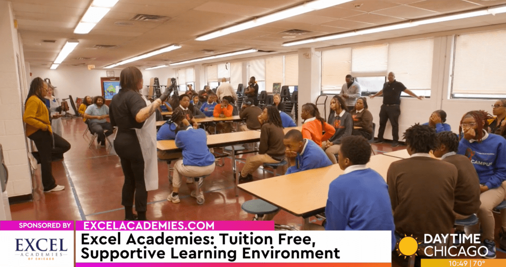 An Excel Academies staff member speaks with students gathered in the school cafeteria.