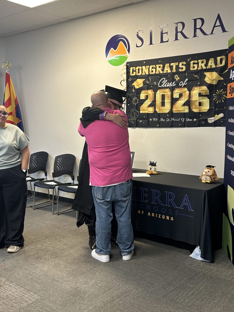 A Sierra School of Gilbert graduate embraces a family member during an emotional Class of 2026 celebration.