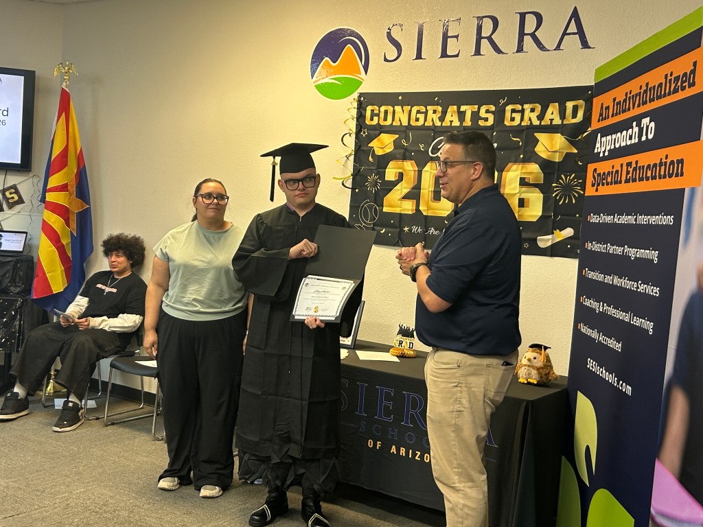 A Sierra School of Gilbert graduate stands with family members while receiving recognition during the Class of 2026 ceremony.
