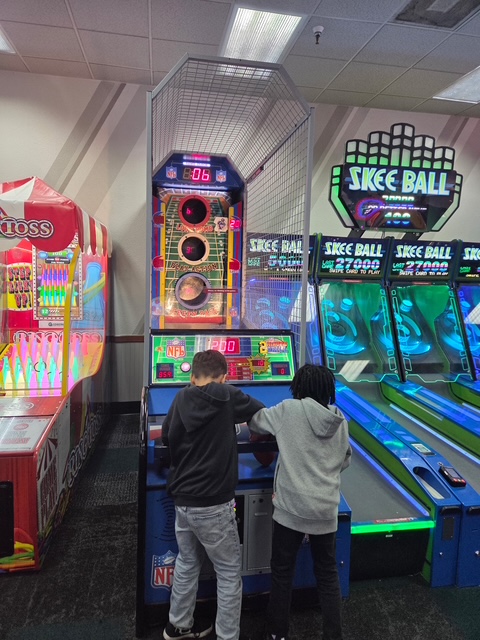 Students work together at an arcade game during a STEAM field trip to Chuck E. Cheese.