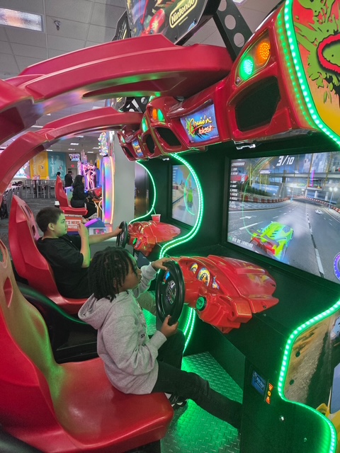 Students practice coordination and decision-making while playing a racing game at Chuck E. Cheese.