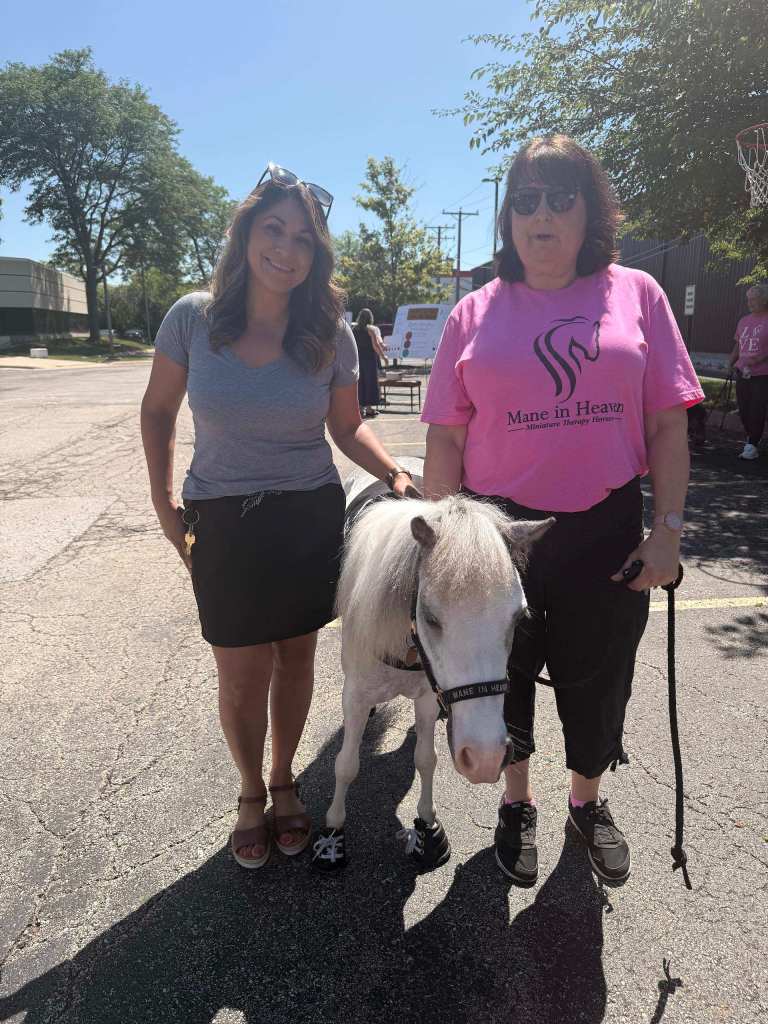 Mental Health Fair attendees standing beside a miniature therapy pony.