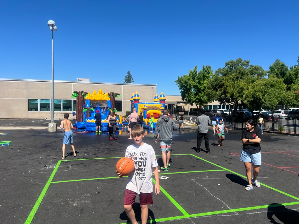 Students play outside near inflatable water slides during a Sierra School of Sacramento summer event.