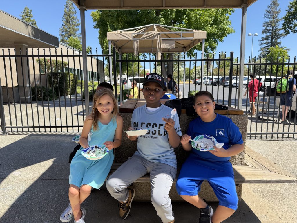 Three Sierra School of Sacramento students smile while enjoying ice cream during a summer activity.